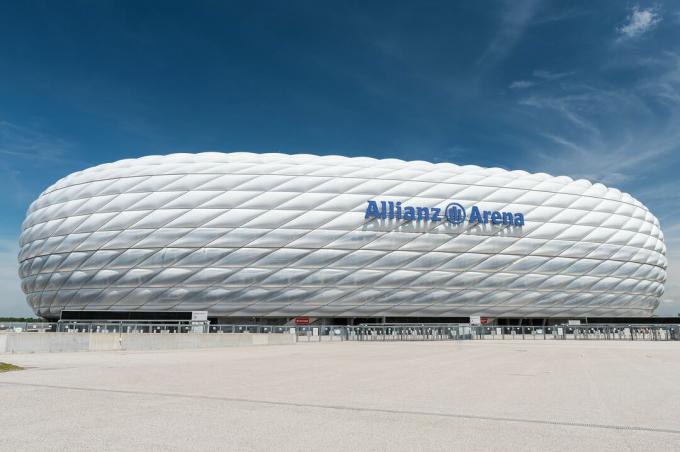 Izliekta sporta stadiona sānskats, piepūstas ETFE plastmasas paneļu skulpturāls ārpuse, kas izskatās kā balta protezēta riepa sānos