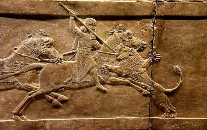 Asīrijas karalis Ašurbanipāls uz zirga, ar šķēpu metot lauvas galvu, metas uz tā