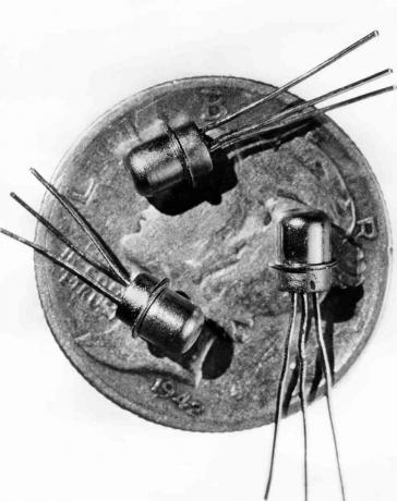 1956. gada attēls ar trīs miniatūriem M-1 tranzistoriem, kas redzami uz santīma sejas