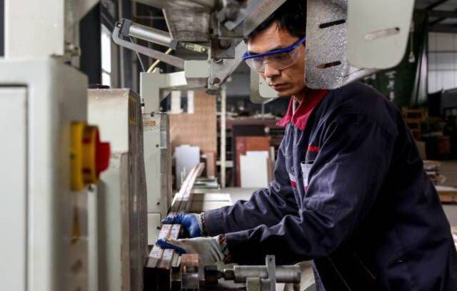 Darbinieks, kas strādā pie alumīnija izstrādājumiem rūpnīcā Zoupingā Ķīnas austrumu Šandunas provincē