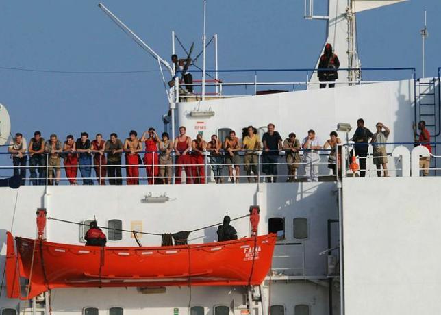 Somālijas pirāti, kas tur rokās tirdzniecības kuģi MV Faina, stāv uz kuģa klāja kopā ar apkalpes locekļiem 2008. gada 19. oktobrī.