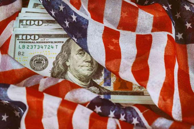 ASV karogs ietīts ap simts dolāru banknotēm.