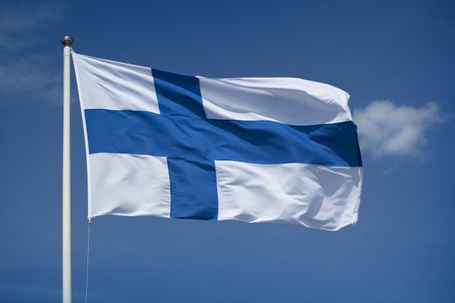 Pacelts Somijas karogs ar zilu debesu fonu